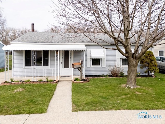 view of front of house with a front lawn, a shingled roof, and covered porch