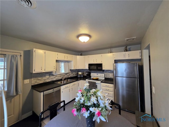 kitchen featuring tasteful backsplash, visible vents, a sink, dark countertops, and stainless steel appliances