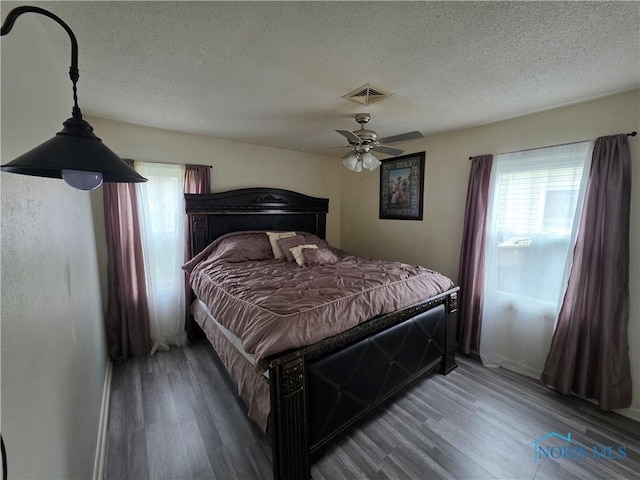 bedroom with visible vents, multiple windows, and wood finished floors