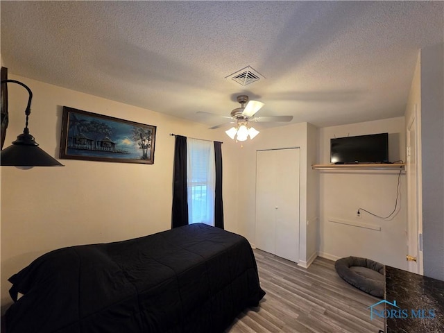 bedroom featuring visible vents, a ceiling fan, wood finished floors, and a textured ceiling