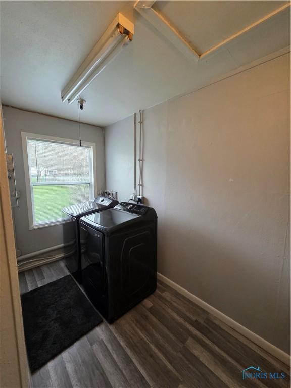 washroom with laundry area, washing machine and clothes dryer, baseboards, and dark wood finished floors