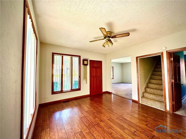 106 Adrian St, Delta, OH 43515 - unfurnished room featuring a textured ceiling, hardwood / wood-style floors, stairway, baseboards, and ceiling fan