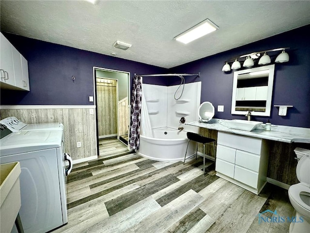 106 Adrian St, Delta, OH 43515 - bathroom featuring washing machine and clothes dryer, wood finished floors, toilet, wainscoting, and a textured ceiling
