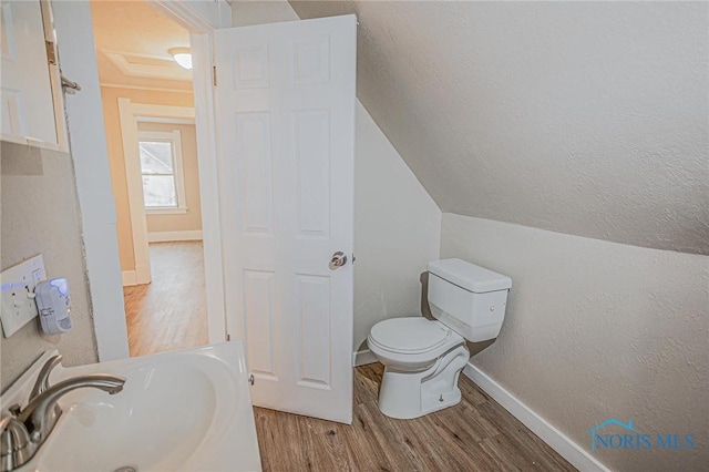 1110 Montrose Ave, Toledo, OH 43607 - bathroom featuring baseboards, a sink, toilet, vaulted ceiling, and wood finished floors