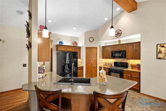 6681 Bellflower Ct, Curtice, OH 43412 - kitchen with black appliances, a peninsula, backsplash, baseboards, and a breakfast bar area