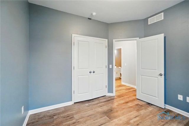 unfurnished bedroom with light wood-style floors, visible vents, baseboards, and a closet