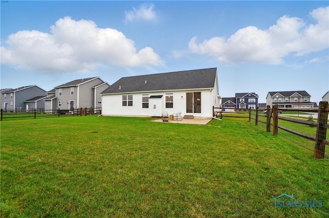 rear view of house with a yard, a fenced backyard, a residential view, and a patio