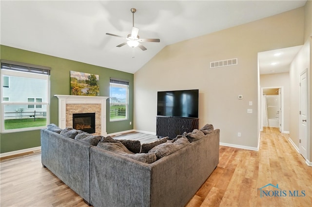 living area with a fireplace, visible vents, light wood-type flooring, and a ceiling fan
