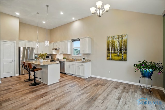 kitchen with light wood-style floors, high vaulted ceiling, white cabinetry, under cabinet range hood, and stainless steel appliances