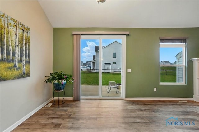 entryway featuring a wealth of natural light, lofted ceiling, wood finished floors, and baseboards