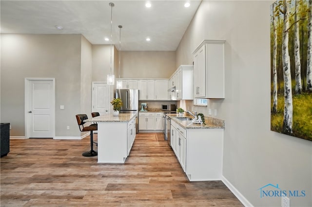 kitchen featuring a breakfast bar, recessed lighting, a center island, a high ceiling, and white cabinetry