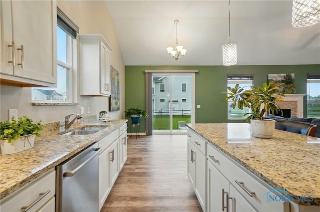 kitchen featuring an inviting chandelier, vaulted ceiling, dishwasher, a sink, and wood finished floors