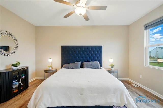 bedroom with light wood-style flooring, baseboards, a ceiling fan, and visible vents