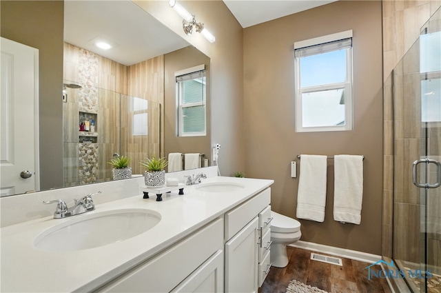 full bathroom with a shower stall, wood finished floors, a sink, and visible vents