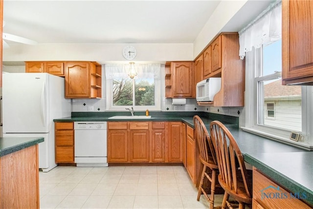 kitchen featuring open shelves, a sink, dark countertops, white appliances, and brown cabinetry