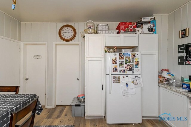 kitchen featuring wood finished floors, freestanding refrigerator, and white cabinets