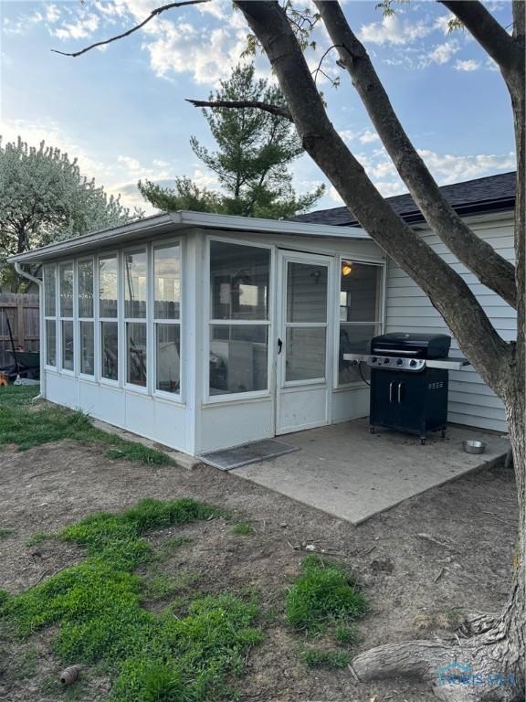 back of property with a sunroom, a patio, and fence