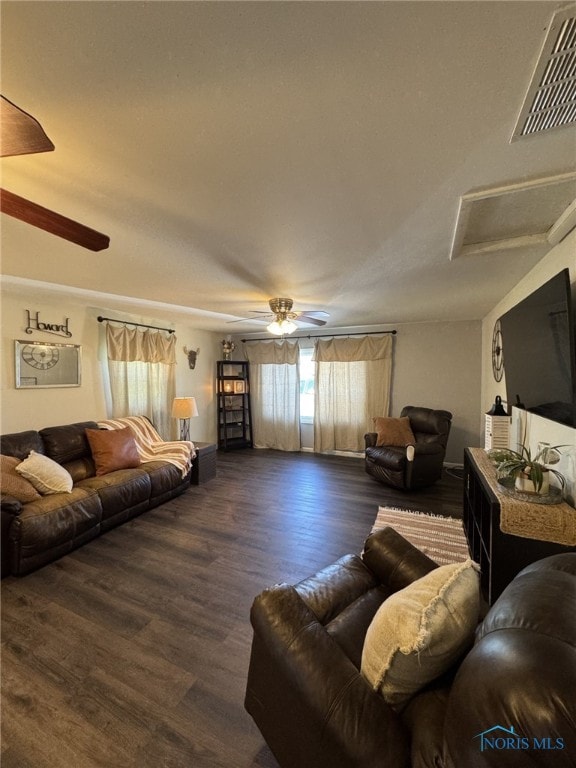 living area with attic access, ceiling fan, wood finished floors, and visible vents