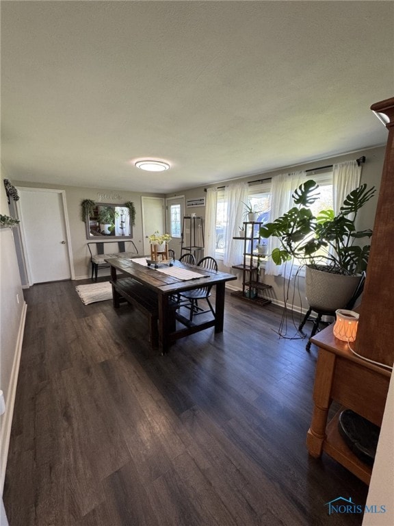 living area with dark wood-type flooring, plenty of natural light, and baseboards