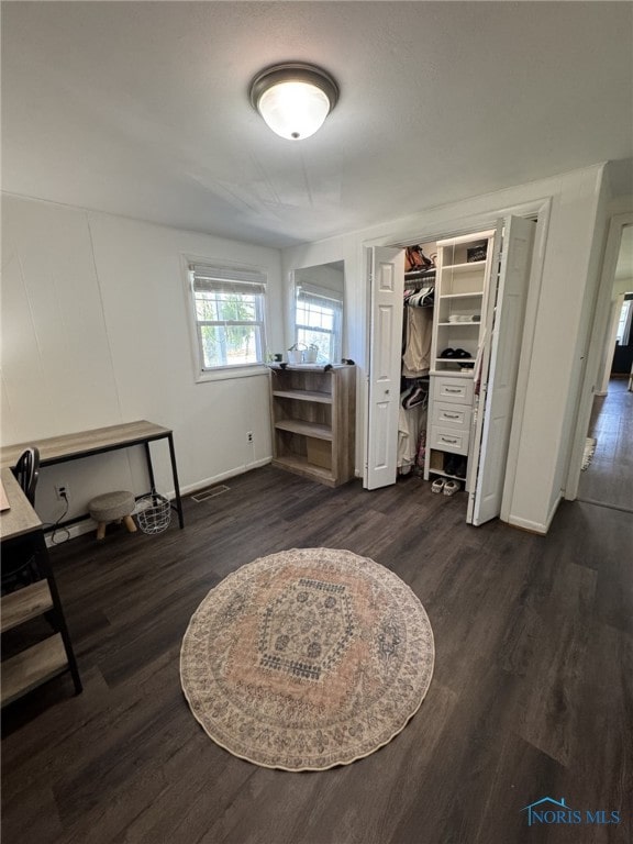 bedroom featuring dark wood-style floors, baseboards, visible vents, and a closet