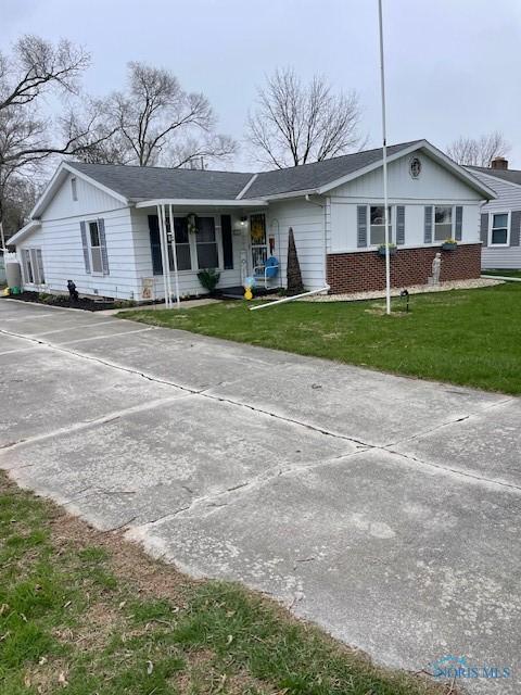 ranch-style home featuring concrete driveway, a front yard, and brick siding