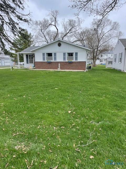 back of house with a lawn and brick siding