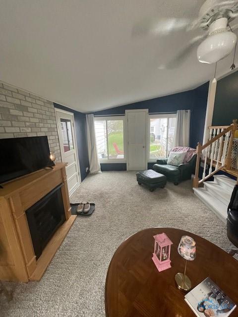 living room featuring carpet, a fireplace, and lofted ceiling