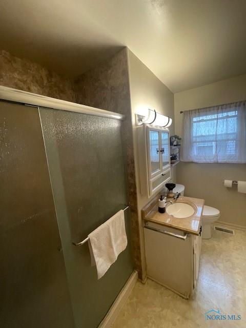 bathroom featuring a shower with door, vanity, baseboards, toilet, and visible vents