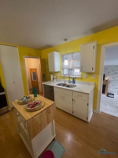 kitchen featuring light wood-type flooring, white cabinets, dishwasher, light countertops, and a sink