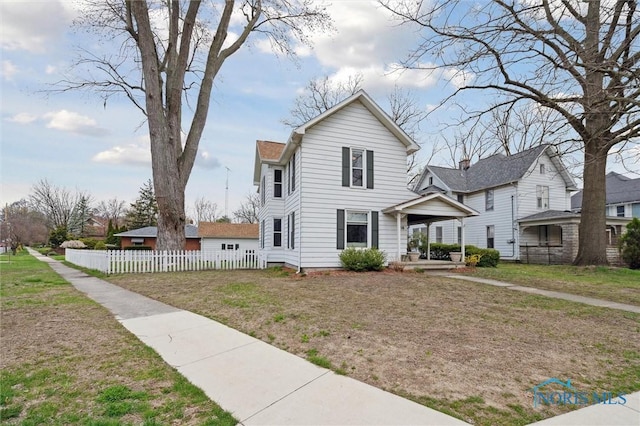 traditional-style home with a front yard and fence