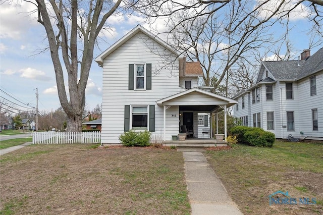 traditional home featuring a front lawn, fence, and covered porch
