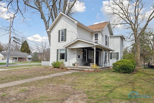 traditional home featuring covered porch and a front lawn