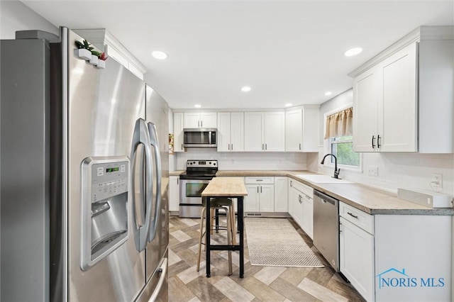 kitchen with decorative backsplash, white cabinetry, a sink, and appliances with stainless steel finishes