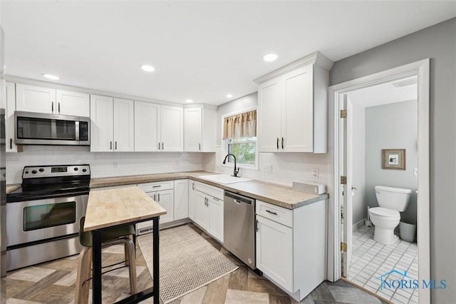 kitchen featuring light countertops, white cabinetry, a sink, and appliances with stainless steel finishes