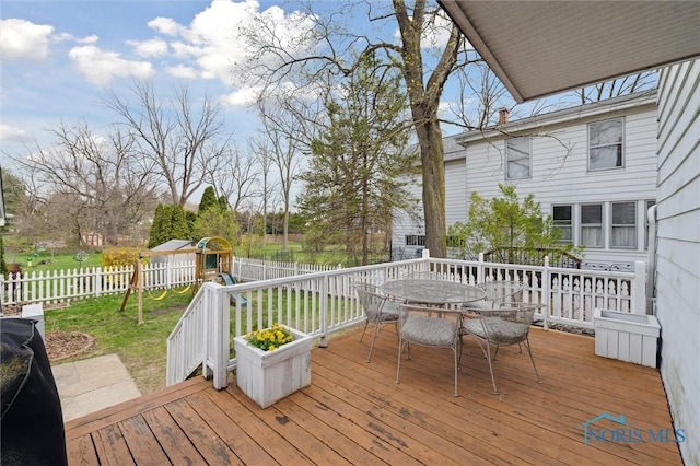wooden deck featuring a fenced backyard, outdoor dining space, and a playground