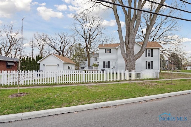 view of front facade featuring a front yard, a fenced front yard, an outbuilding, and a detached garage
