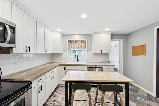 kitchen featuring tasteful backsplash, white cabinets, a sink, light countertops, and stainless steel appliances