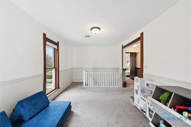 sitting room featuring visible vents, carpet flooring, and an upstairs landing