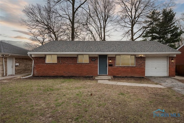 single story home featuring an attached garage, roof with shingles, a front yard, and brick siding