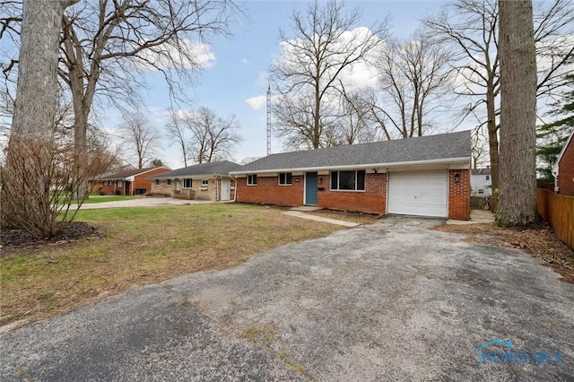 ranch-style home with brick siding, an attached garage, fence, and aphalt driveway