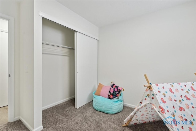 carpeted bedroom featuring a closet and baseboards