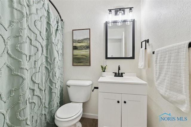 bathroom featuring vanity, a shower with curtain, toilet, a textured wall, and baseboards