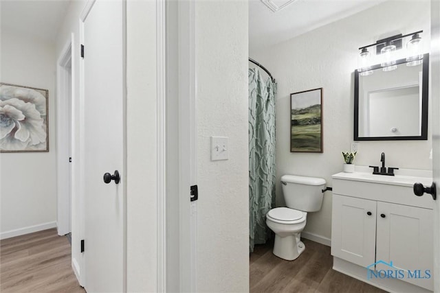 full bath with baseboards, a shower with curtain, toilet, vanity, and wood finished floors