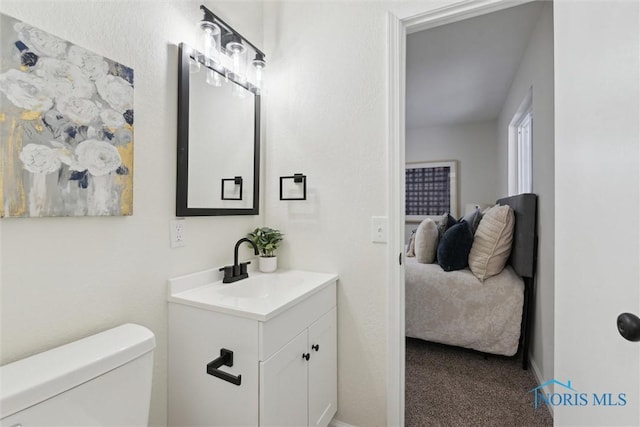bathroom with ensuite bath, toilet, vanity, and baseboards