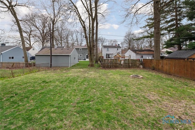 view of yard featuring a residential view, a fenced backyard, and a fire pit