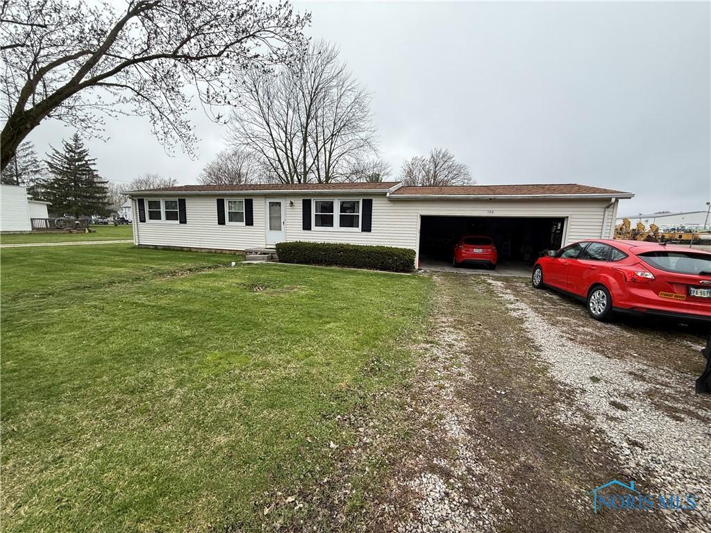 ranch-style home featuring driveway, an attached garage, and a front lawn