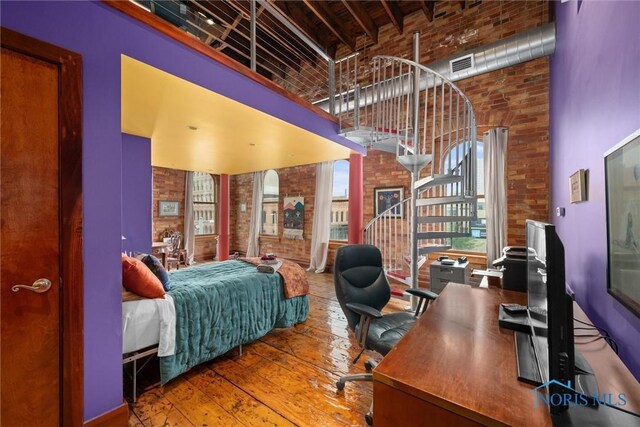 1 S Saint Clair St, Toledo, OH 43604 - bedroom featuring brick wall, visible vents, a high ceiling, and hardwood / wood-style floors