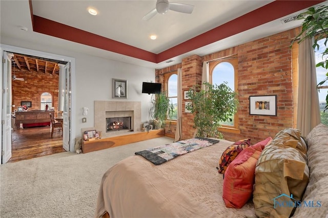 1 S Saint Clair St, Toledo, OH 43604 - carpeted bedroom featuring a tile fireplace, brick wall, a ceiling fan, and visible vents