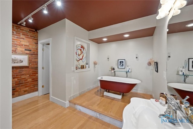 1 S Saint Clair St, Toledo, OH 43604 - full bathroom with baseboards, track lighting, brick wall, a freestanding bath, and wood finished floors
