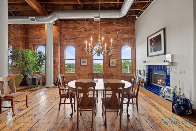 1 S Saint Clair St, Toledo, OH 43604 - dining space with visible vents, a notable chandelier, brick wall, hardwood / wood-style flooring, and a fireplace